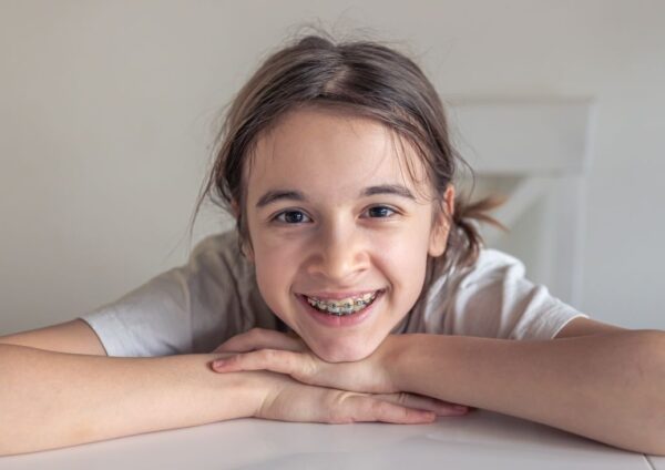 A smiling child with braces on their teeth, representing the importance of early orthodontic treatment for crooked teeth in kids