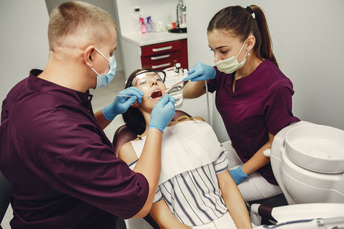 Dentist and assistant examining a patient for full mouth restoration in Kolkata at a modern dental clinic.
