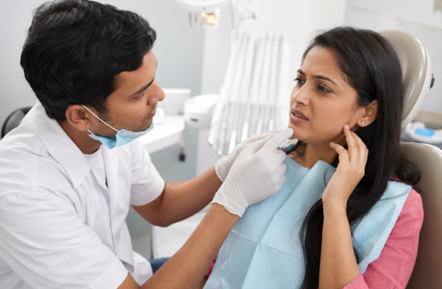 Indian woman discussing jaw discomfort with a dentist during a dental implant check-up inside a modern dental clinic.